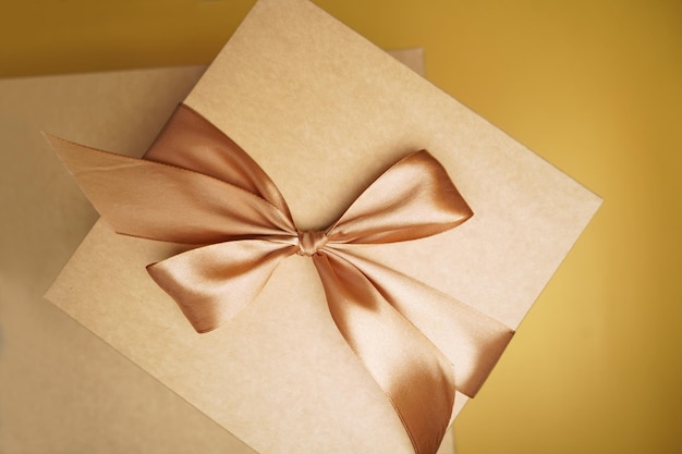 square gift box craft paper yellow color bow knot ribbons paper background empty label sticker for text happy new year package top view