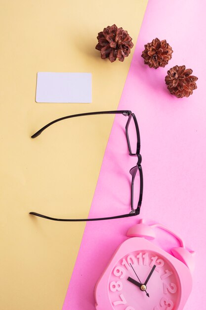 Square glasses in the photo in minimal summer style on a pastel pink and yellow background. Alarm Clock , Pine Tree Flowers , Business Cards