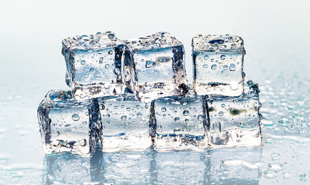 Квадратные тающие кубики льда на мокром столе