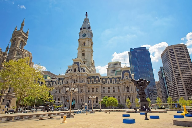 Square near philadelphia city hall with sculptures such as\
government of the people sculpture. tourists, philadelphia city\
hall and church on the background. pennsylvania, usa.