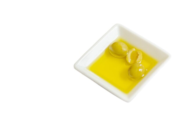 Square plate with olive oil and green olives copyspace