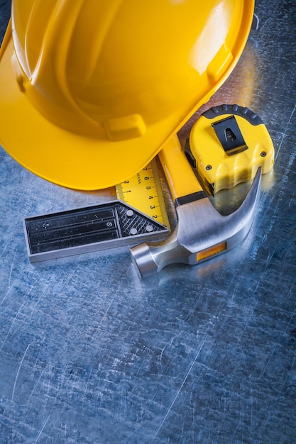 Square ruler measuring tape protective hard hat and claw hammer on scratched metallic surface construction concept