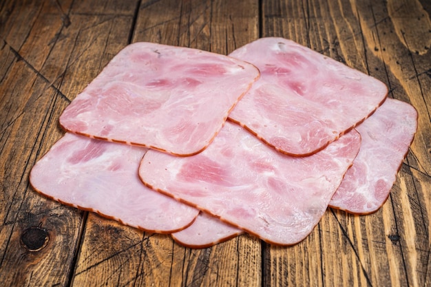 Square Slices of pork ham on wooden table. Wooden background. Top view.