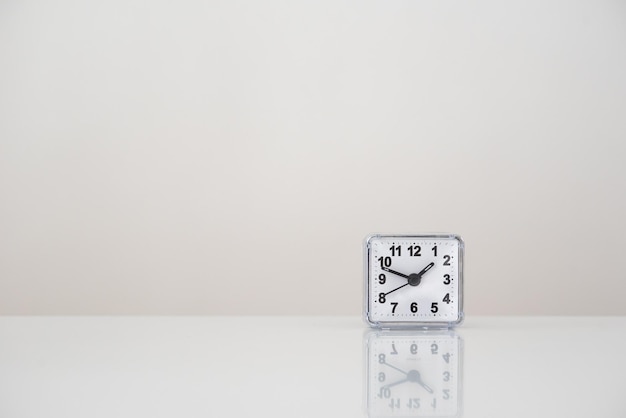 Square white clock on a white table Time management