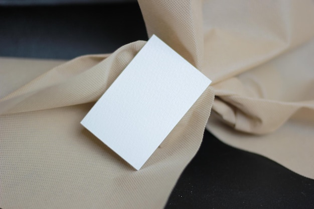 a square of white paper is laying on a piece of brown cloth
