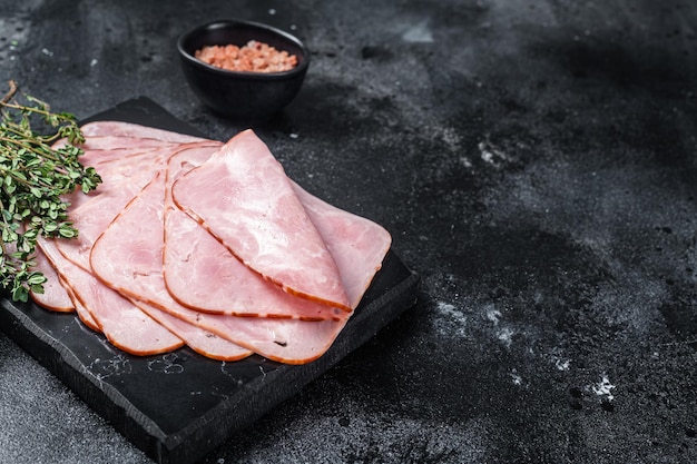 Squared slices of lean pork ham. Black background. Top view. Copy space.