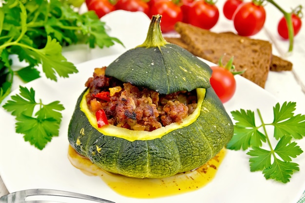 Squash green stuffed with meat, tomatoes and peppers in the dish, bread, garlic and parsley on a wooden board background