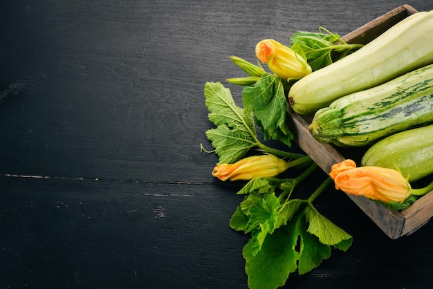 Squash Marrow courgette in een houten kist op een zwarte tafel Bovenaanzicht Ruimte kopiëren