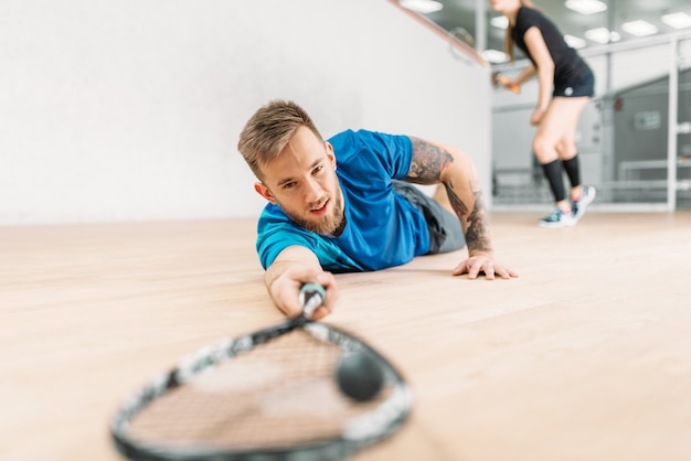 Squashtraining, mannelijke speler met racket ligt op de grond.