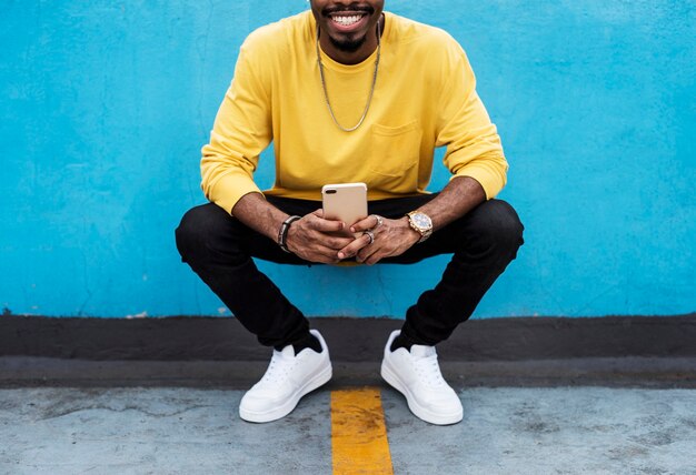 Squatting young man using his mobile phone