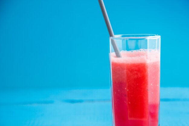 Squeezed watermelon juice in a transparent glass on a blue wooden background