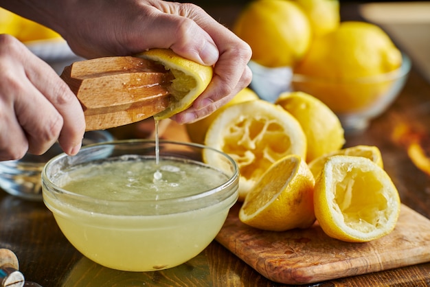 Выдавливание свежего лимонного сока с деревянной пастой в миску