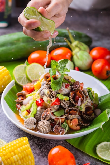 Foto spremere vongole al limone insalata delizioso cibo tailandese posto sul tavolo decorato con varie giornate del cibo di verdure