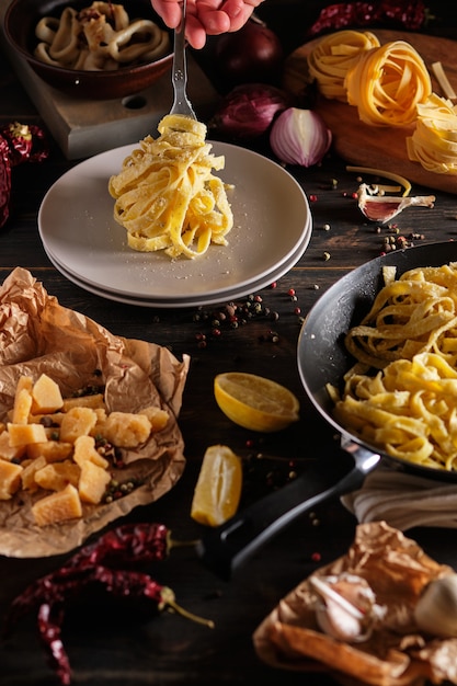 Photo squid pasta in a creamy sauce with parmesan cheese hands of the cook in the frame