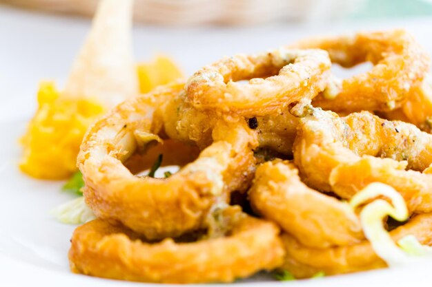 Foto anelli di calamari serviti con una varietà di lattuga e condimento di frutta aromatica.