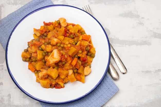 Squid stew with vegetables in white dish on ceramic