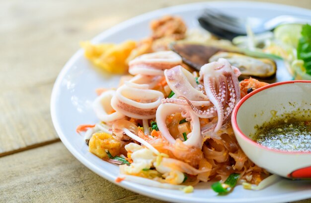 Calamari su spaghetti di riso saltati in padella (pad thai) con cozze.