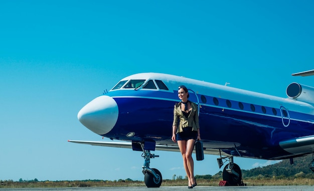 Ssmiling stewardess die dienst doet op de achtergrond van het volledige transporttoerisme en luchtvlucht op de achtergrond van het vliegtuig