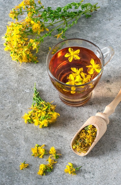 St. John's wort drink and Hypericum flowers on stone table. Top view.