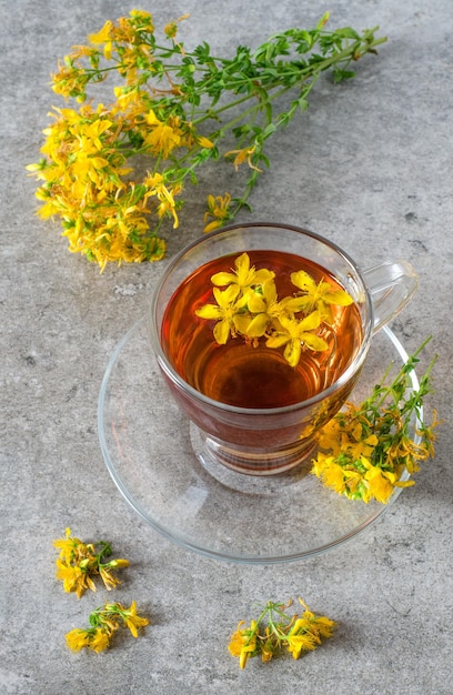 St. john's wort tea in glass cup and hypericum flowers on stone table. top view. ãâãâãâãâ¡lose-up