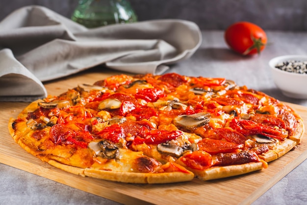 St Louis Style pizza met spek, champignons, tomaten en paprika's op een bord op tafel