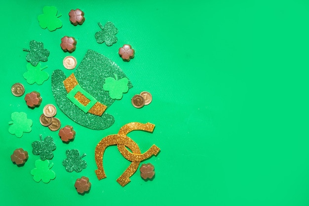 St patrick flatlay background with shamrock clover leaves leprechaun hat decor golden coins and chocolates in form of symbol of st patrician day