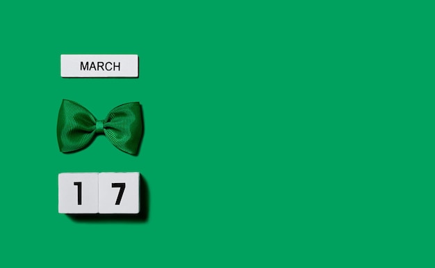 Sfondo del giorno di san patrizio calendario in legno con un arco leprechaun su sfondo verde.copia spazio