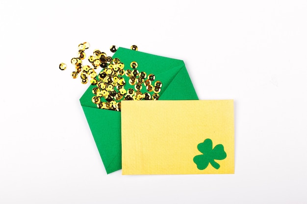 St. Patrick 's Day concept. Empty card with green envelope and gold confett and clover leafi. Mockup template. View from above