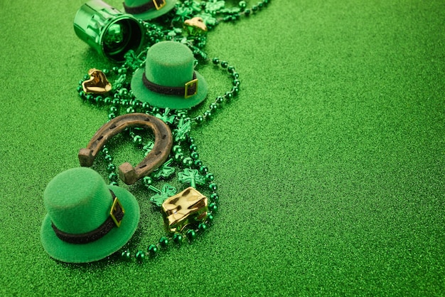 St patrick's day hoekrand van klavers gouden munten en kabouterhoed over een glinsterende groene achtergrond