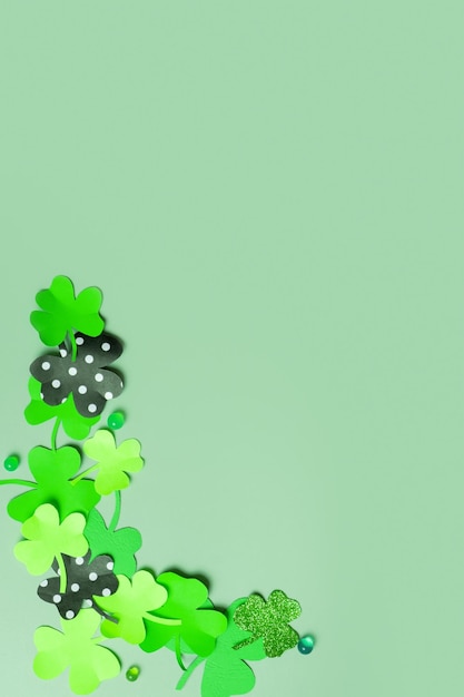 St Patrick's Day minimalistic concept Paper clover leaves on colored vertical background with copy space