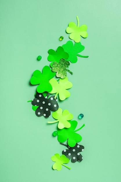 St Patrick's Day minimalistic flat lay composition Paper clover leaves on colored background with copy space