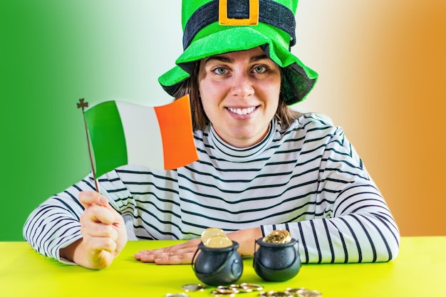 St Patrick39s Day Mooie vrouw met groene hoed houdt vlag en pot met gouden munten op bureau