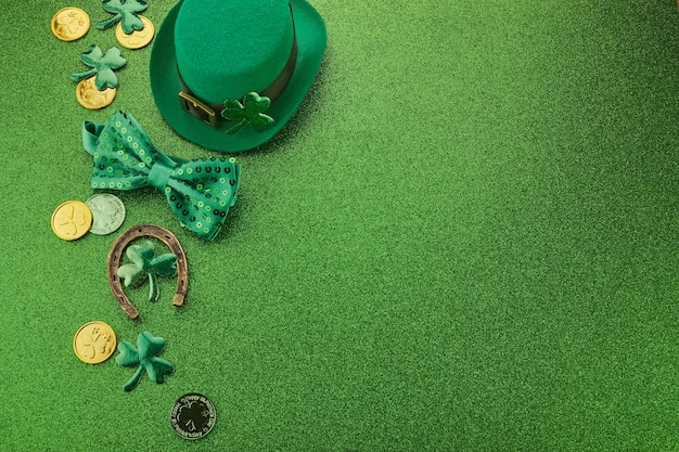 St patricks day frame of shamrocks gold coins and leprechaun hat over a glittery green background