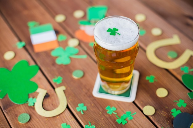 st patricks day holidays and celebration concept glass of draft beer shamrock and gold coins on wooden table