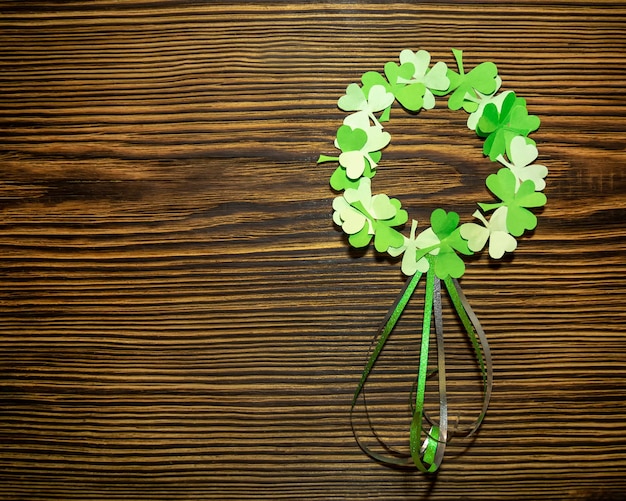 St patricks day paper wreath of clover leaves on a brown wooden
background