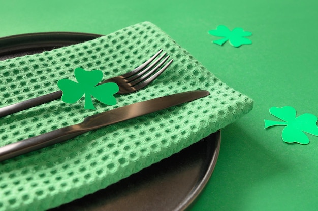 St patricks day table setting with shamrock clover leaves on green background