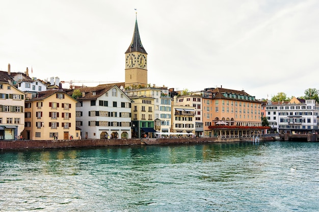 St Peter Church aan de kade van de rivier de Limmat in het centrum van Zürich, Zwitserland. Mensen op de achtergrond