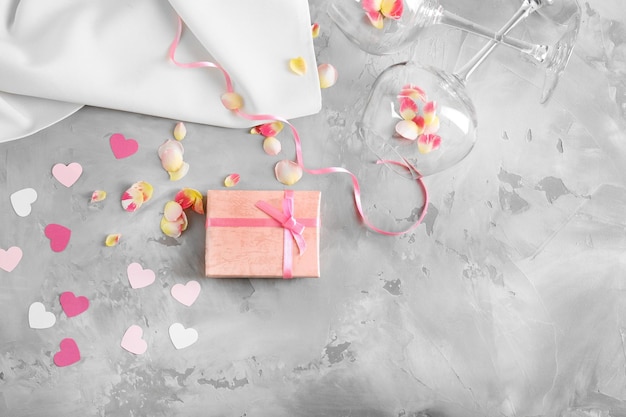 St Valentijnsdag concept Geschenkdoos bloemblaadjes en lege wijnglazen op tafel