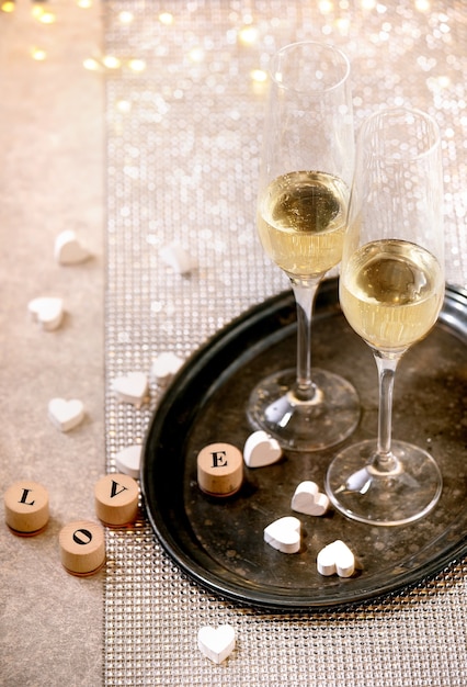 St. Valentine or wedding greeting card with two Champagne glasses on tray standing on silver sparkling table