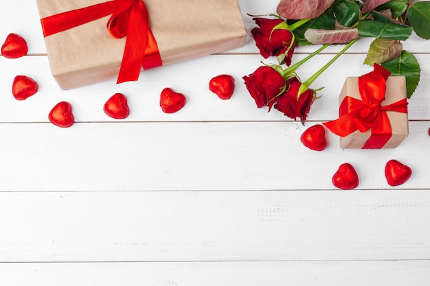 St. Valentines Day background. Red roses and gift box on wooden table