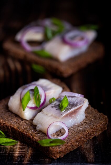 Foto staan met een hapje van roggebrood, haring en uien