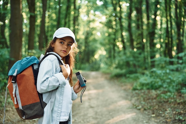 Staande met een verrekijker in handen Meisje is in het bos op zomerdag om nieuwe plaatsen te ontdekken