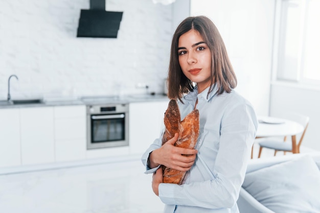 Staande met stokbroden Jonge vrouw is overdag binnenshuis in de kamer van een modern huis