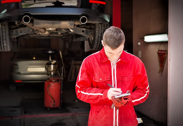 Staande motormonteur die aantekeningen maakt voor een zwarte sedan