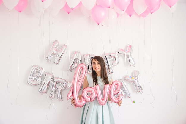 Staande vrouw in decoraties met ballonnen en confetti voor verjaardagsfeestje