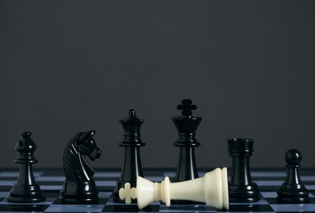 Staande zwarte schaakstukken en liggende witte koning
