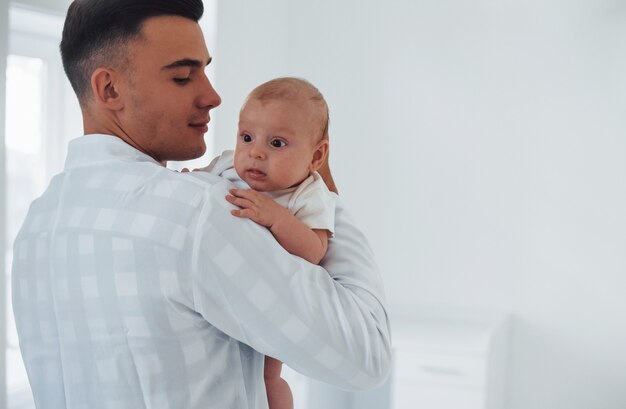 Staat en houdt de baby op de handen. De jonge kinderarts is overdag in de kliniek.