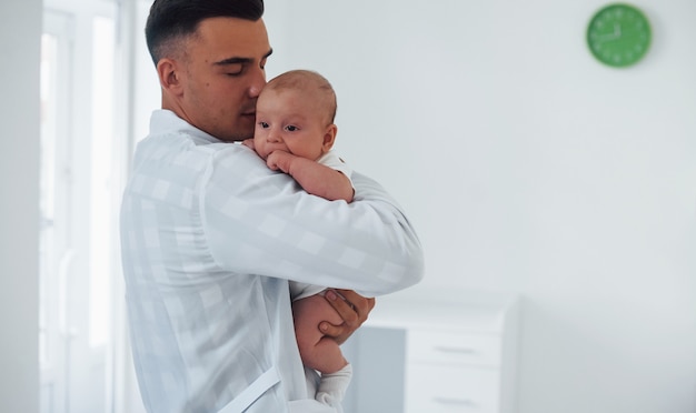 Staat en houdt de baby op de handen. De jonge kinderarts is overdag in de kliniek.