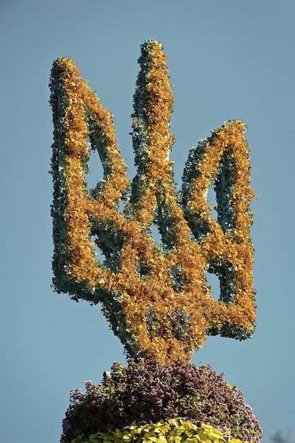 Foto staatswapen oekraïne gemaakt van bloemen blauwe hemelachtergrond onafhankelijkheidsdag tryzub concept blauw schild met gouden drietand symbool oekraïne oekraïne viert onafhankelijkheid op 24 augustus