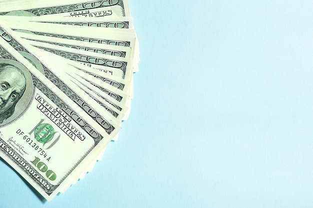 Пачка банкнот по 100 долларов на голубом фоне, сто долларов. Концепция Бизнес, финансы, инвестиции, оплата наличными, сбережения и богатство. Копировать пространство